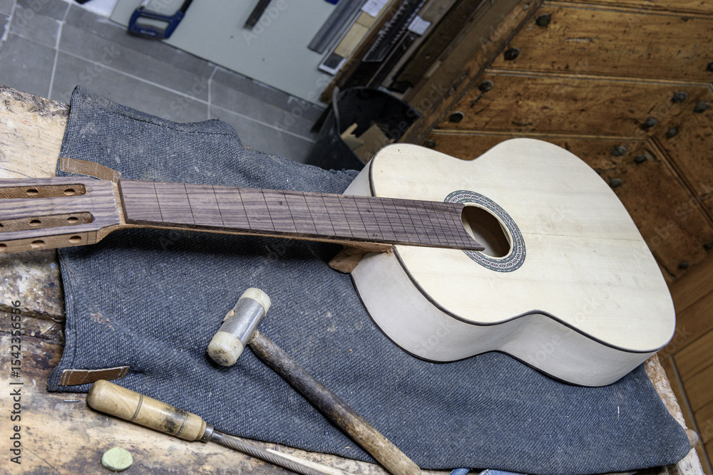 Fototapeta premium Handcrafted guitar with unfinished neck on workbench
