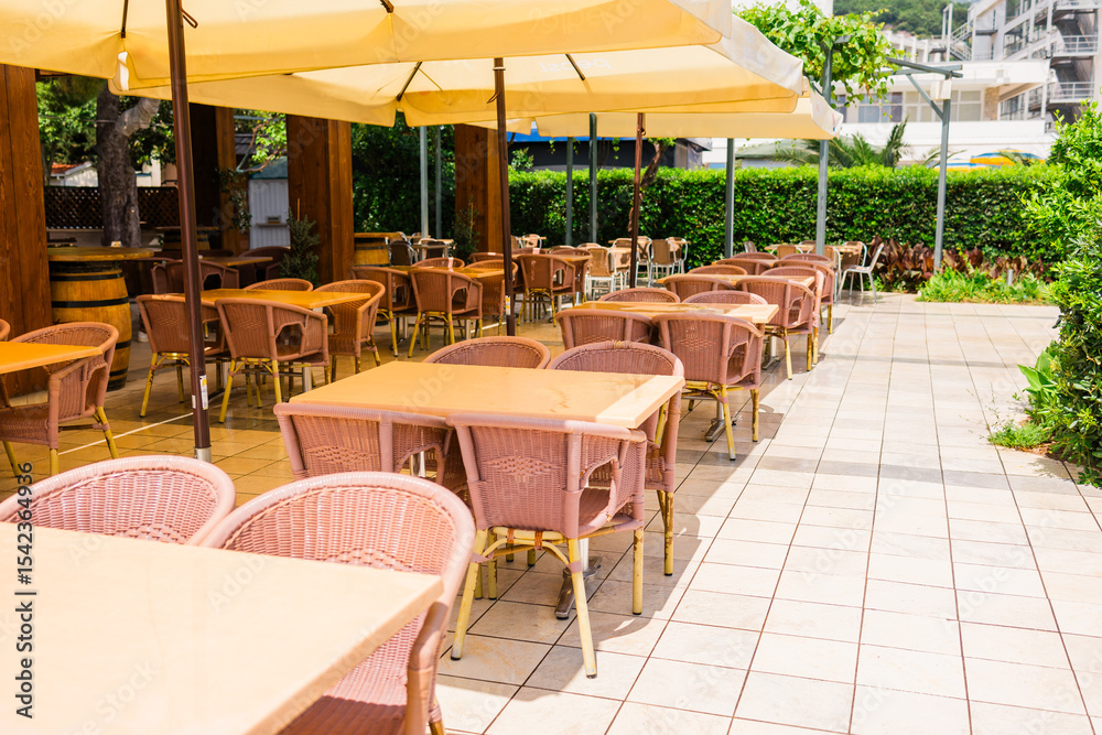 Obraz premium Modern restaurant terrace with set tables and chairs. Casual dining, cozy atmosphere, and summer hospitality experience.
