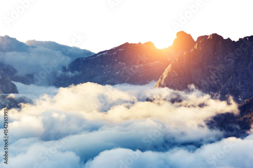 Majestic mountain peaks emerging through clouds at sunrise with a warm glow