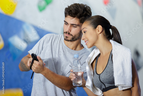 man and woman discussing by climbing wall in gym