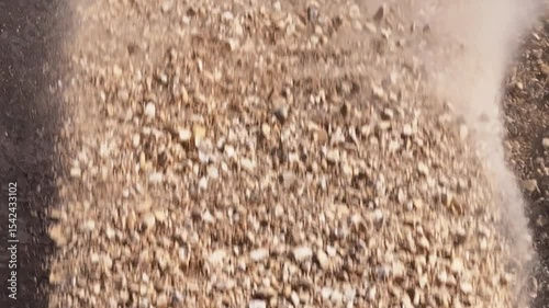 Top-down aerial view of a conveyor belt discharging a powerful stream of crushed stone and dust, creating a stockpile at an industrial quarry or construction site.

