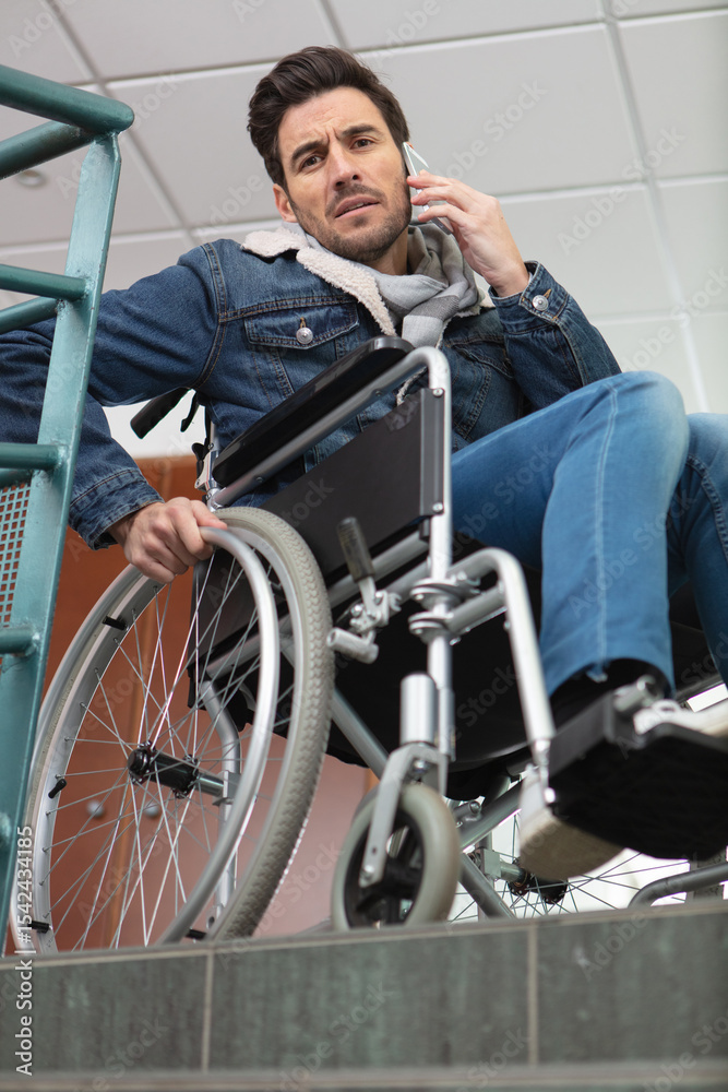 worried man in wheelchair at top of staircase worried man in wheelchair at top of staircase
