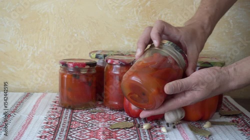 canned pepper in jars, canned pepper in jars, in the hands of jars with sweet red pepper