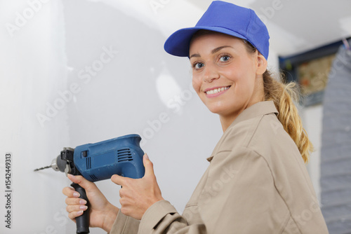mid-adult woman drilling hole in wall