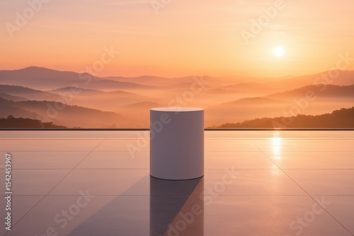 Minimalist outdoor scene with cylinder sculpture at sunrise overlooking misty mountains