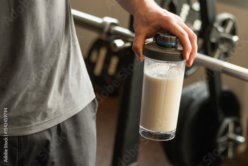 Close up of man hand with protein shaker at gym. Fitness healthy lifestyle concept. Supplement product, creatine, glutamine for workout.