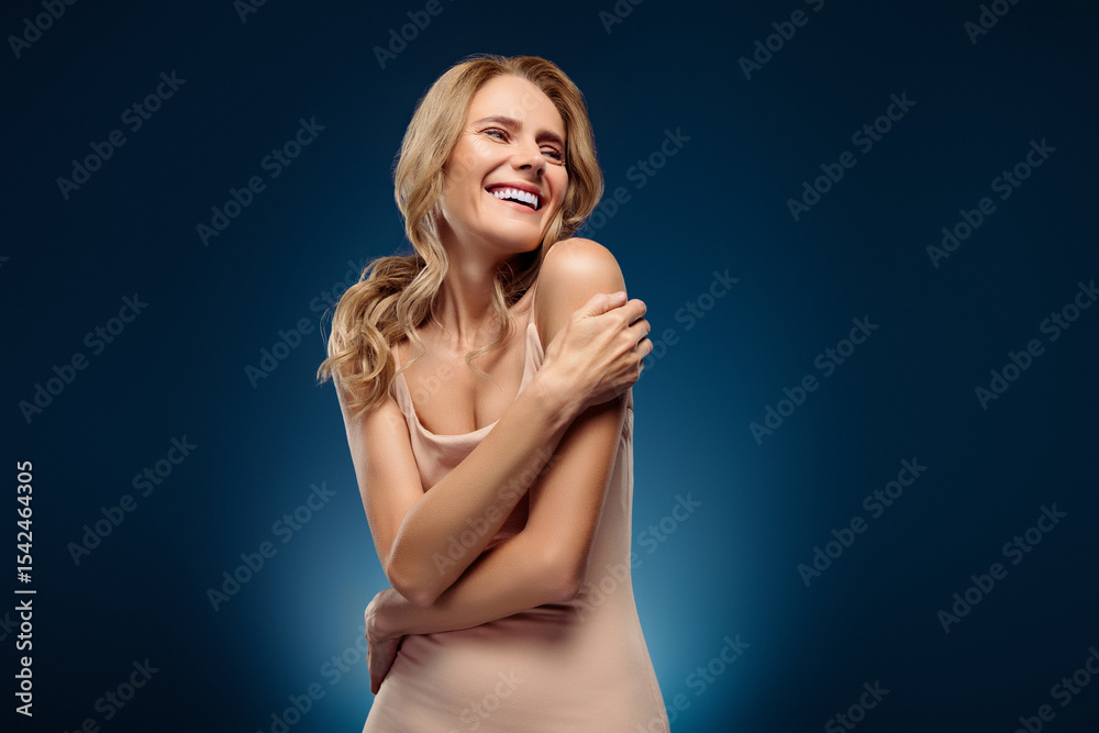 Fototapeta premium Elegant mature woman with radiant smile and blonde hairstyle exuding beauty and confidence against a blue background
