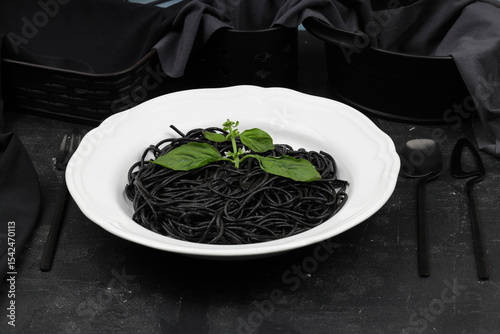 Spaghetti pasta with black ink squids on wooden background.