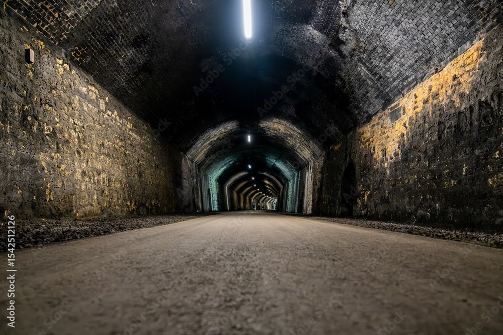 Naklejka premium Long dark tunnel with lights disappearing into the distance