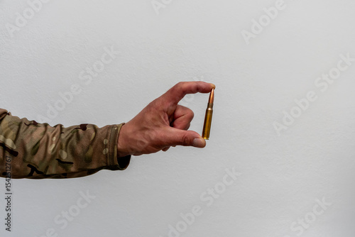 A single cartridge in the hand of a soldier. Minimalistic image conveying the theme of weaponry, war and the decisive shot.