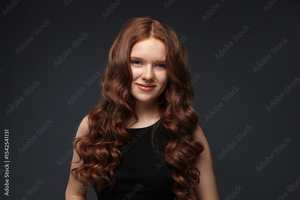 Fototapeta premium Portrait of beautiful teenage girl with healthy wavy hair on dark grey background