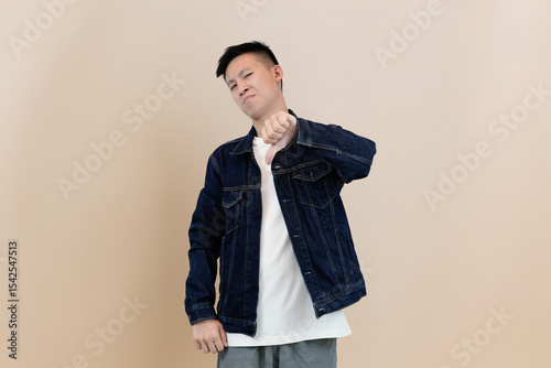 young asian man giving thumbs down showing disapprove or rejection in studio background