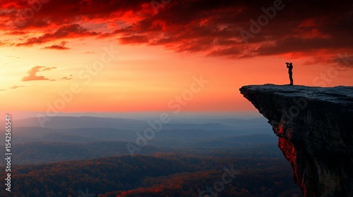 Silhouette of a person on a clifftop at sunrise, panoramic view of mountains and valleys
