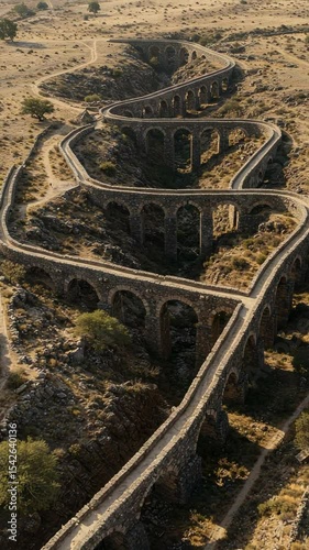 Aerial View of an Ancient Stone Aqueduct Surrounded by Rocky Terrain and Vegetation