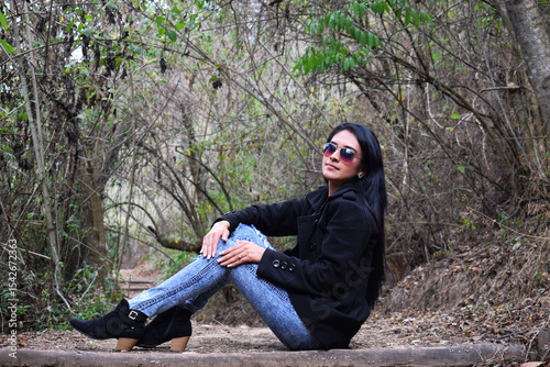 Sesión de fotos de invierno, chica bonita usando un abrigo negro, pantalón azul y zapatos negros. Concepto de moda, belleza y estilo.