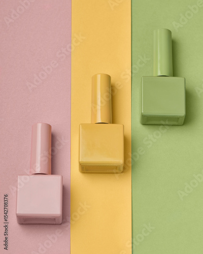 Green, butter yellow and pink varnish bottles for female manicure, beauty salon glamour, gel nail design. Background for glamour beauty salon