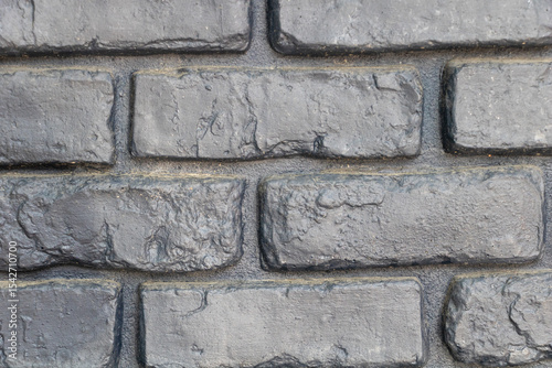 A close-up of the texture and details on a grey brick wall, showcasing the different sizes and shapes of the bricks.