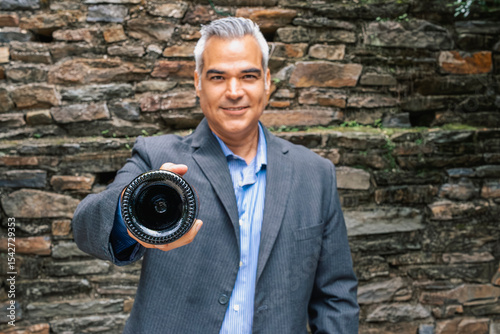 Confident hispanic gray-haired Businessman Offering a Wine Bottle