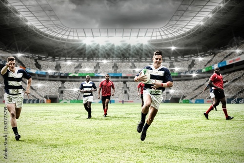 Two teams of rugby players playing rugby in sports stadium