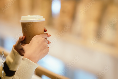 A young woman wearing headphones and glasses, appearing to be an East Asian female, intently uses a white laptop at a cafe table. photo
