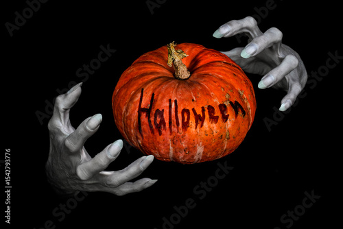 Bony pale monsters hands with sharp nails and pumpkin with lettering Halloween between them, isolated on black.