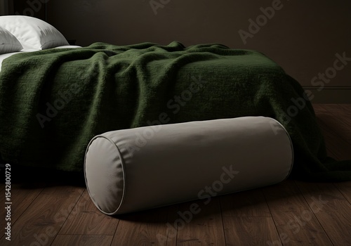 Cozy bedroom scene featuring a bolster pillow and a draped green blanket on a bed