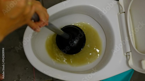 A woman's hand is using an air pump to solve a clogged toilet.
