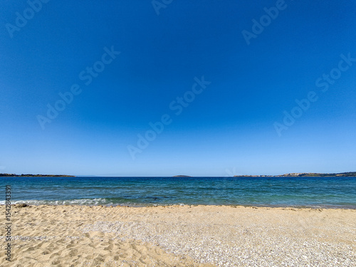 Beach, sea, empty sky and island in the distance