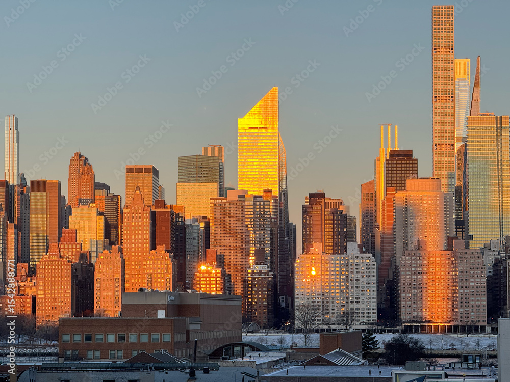 Obraz premium New York skyscrapers at sunrise. A cluster of high-rise buildings shining red. From the observation deck of a building in Long Island City.
