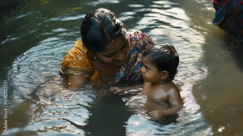 Indian woman bathing her baby in a river, traditional scene of rural life in India, hygiene practices in poor areas of India, mother washing her baby in a river, concept of poverty and destitution in 