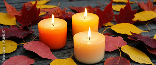 Lit candles in autumn colors, surrounded by vibrant fall leaves, creating a warm, cozy, and festive atmosphere. AI generated.
