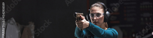 Foto Header of young Caucasian woman wearing protective glasses and earmuffs aiming h