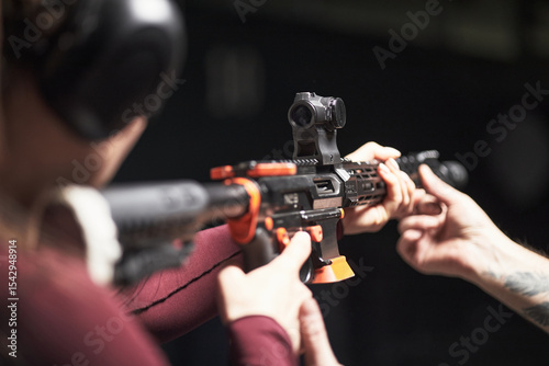 Photography Anonymous female customer wearing protective earmuffs aiming rifle at shooting c
