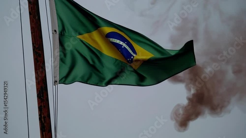 Torn Brazil flag, stained with black ink and warped by heat, waves through smoke and ashes. A powerful visual metaphor of corruption, destruction, and national decay