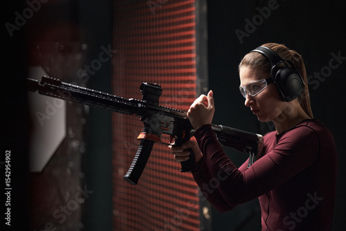Photos Caucasian young woman wearing protective glasses and earmuffs, holding rifle, pr
