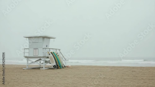 A lifeguard stand on a beach, with surfboards leaning against it, on a hazy day