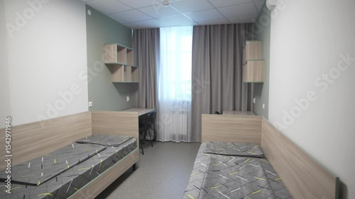 Cozy university dorm with study desks flanked by lofted single beds with storage drawers. Wooden bookshelves maximize space in living area