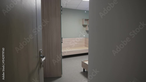 Long dormitory corridor stretches into distance with identical numbered doors. Freshly waxed linoleum flooring reflects overhead lighting