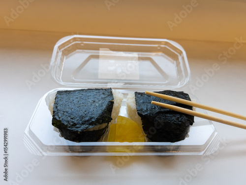 Japanese onigiri rice balls with nori seaweed and takuan pickles, purchased from a combini. A convenient and quick snack, typical of Japanese street food and takeout meals.