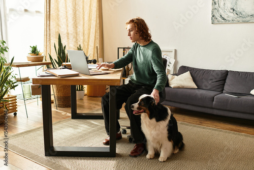 Obraz na plátne Young man enjoys a cozy afternoon at home with his loyal dog by his side while w
