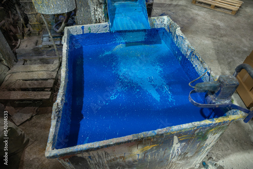 фотографія Vibrant blue paint tank in a bustling factory setting, capturing the essence of industrial artistry