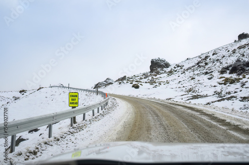 CHAIN BAY AHEAD road sign on a frozen snow mountain road. Wanaka. Otago Region. South Island.