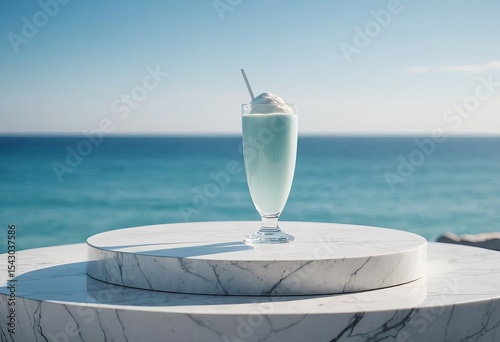 Mint milkshake in glass on round marble table by the ocean  