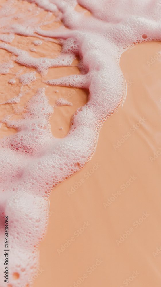 Fototapeta premium Macro photograph of pink foamy liquid with ripples and bubbles against a peach-colored background