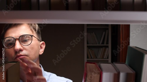 Researcher smiling and choosing a book from a bookshelf in the library