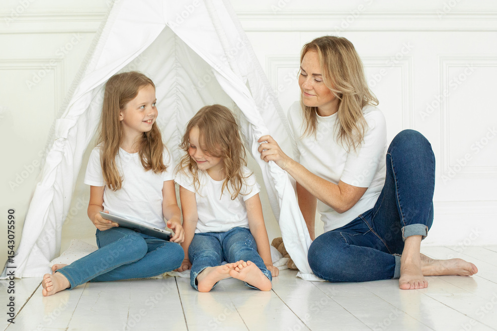 Obraz premium Happy mother and two daughter. Family using tablet gadget at home