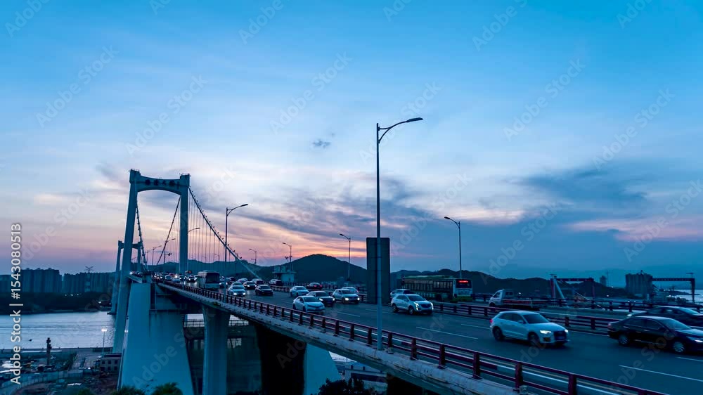 Xiamen Haicang Bridge evening traffic timelapse showcasing busy commute across the waterway under colorful sunset skies Xiamen Haicang Bridge evening traffic timelapse showcasing busy commute across the waterway under colorful sunset skies