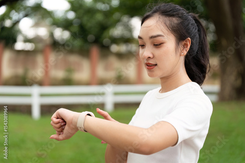 Fitness and Wellness. Young woman checking smartwatch while preparing for outdoor exercise.
