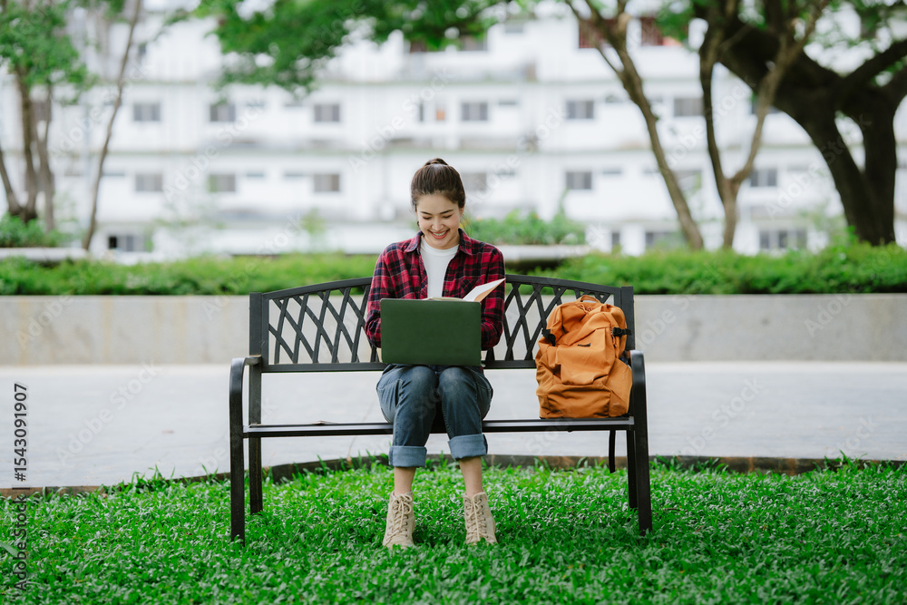Fototapeta premium Young asian woman relaxing reading book sitting at public park life style outdoor. Happy female Take a break enjoy time living in the nature. Human and nature together