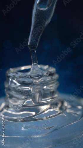 Glass pipette with facial serum on a light background. Essential oil close-up in a pipette. A skin care product with hyaluronic acid in a pipette.